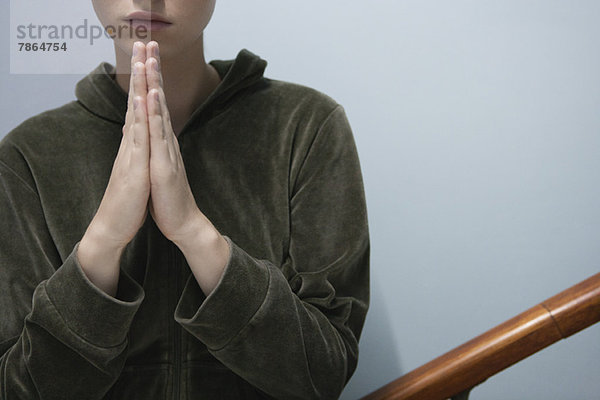 Junge Frau mit im Gebet umklammerten Händen  abgeschnitten