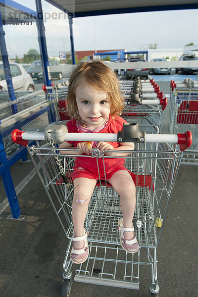 Kleines Mädchen sitzt im Einkaufswagen