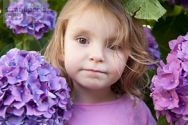 Kleines Mädchen umgeben von Hortensienblüten  Portrait