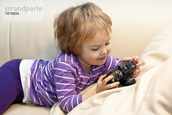 Blondes Mädchen mit Digitalkamera auf der Couch