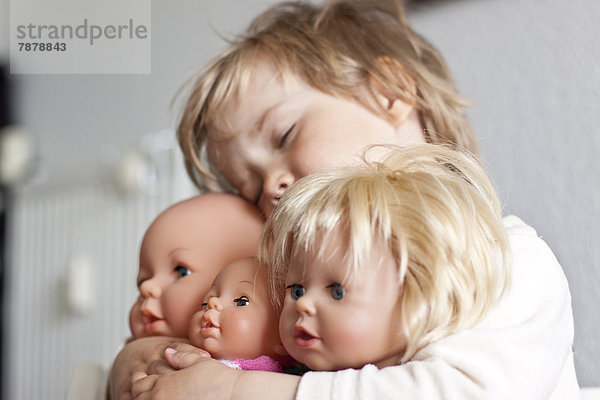 Blondes Mädchen umarmt ihre Puppen