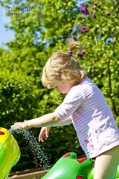 Blondes Mädchen spielt im Garten