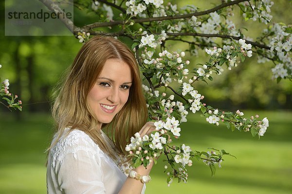 Junge Frau an einem blühenden Apfelbaum  Portrait