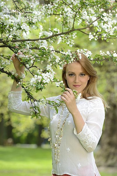 Junge Frau an einem blühenden Apfelbaum  Portrait