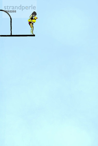 Mädchen mit Schwimmreifen steht am Rand eines Sprungturms