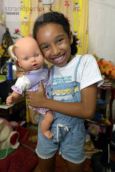 Mädchen  lächelnd  mit einer Puppe in einer Wohnung in einem Armenviertel  Favela ***KEINE VERÖFFENTLICHUNG IN BRASILIEN***