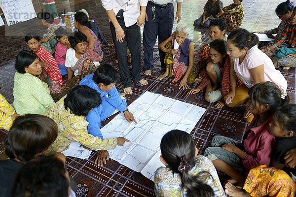 Männer und Frauen aus dem Dorf diskutieren mit Vertretern einer Hilfsorganisation über einer Karte  in der die Quellen und Brunnen ihres Dorfes eingezeichnet sind  Probleme und Potentiale der Wasserversorgung der Gemeinde werden analysiert