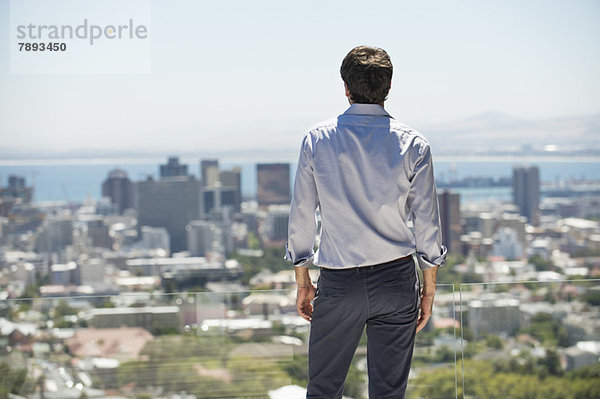 Mann auf der Terrasse mit Blick auf eine Stadt