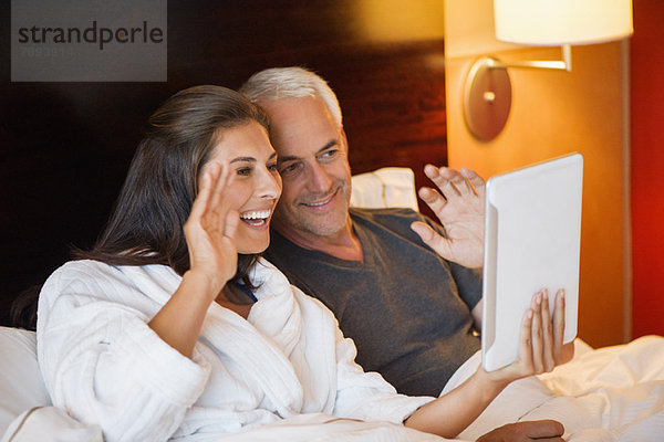 Paar Videoanrufe auf einem digitalen Tablett in einem Hotelzimmer
