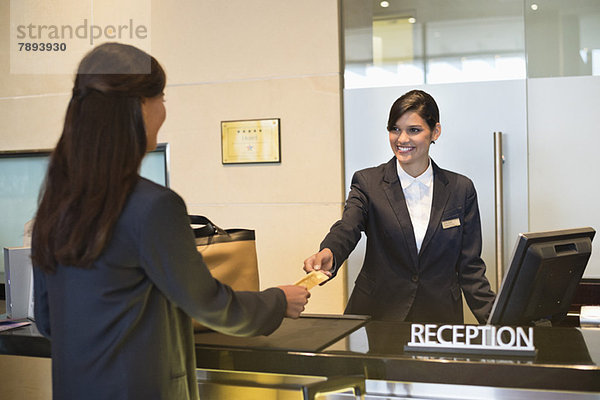 Geschäftsfrau beim Bezahlen mit Kreditkarte an der Hotelrezeption
