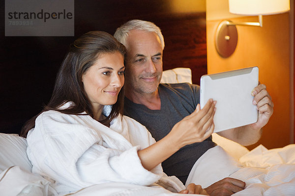 Ein Paar schaut sich einen Film auf einem digitalen Tablett in einem Hotelzimmer an.