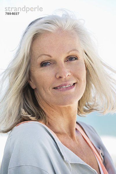 Porträt einer am Strand lächelnden Frau