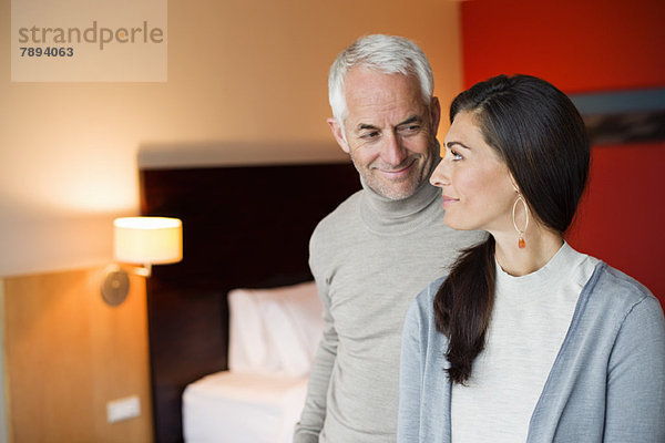 Paar lächelt in einem Hotelzimmer