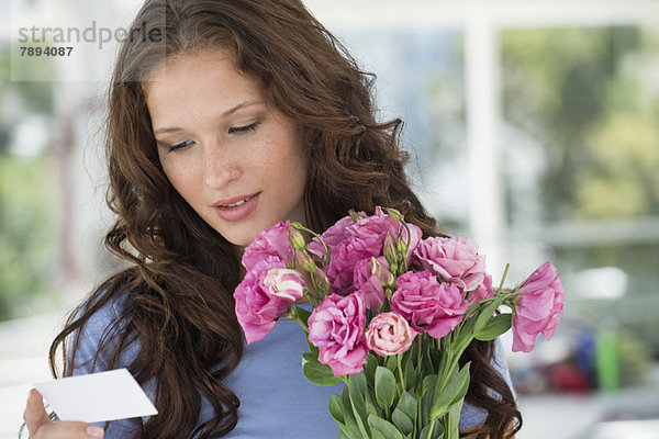 Frau beim Lesen einer Karte mit Blumenstrauß