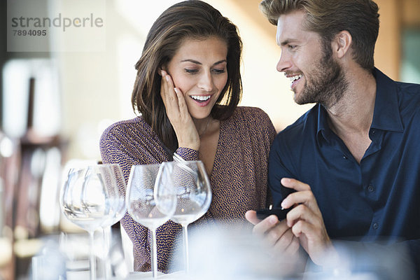 Mann mit Verlobungsring  der seine Freundin in einem Restaurant vorschlägt.