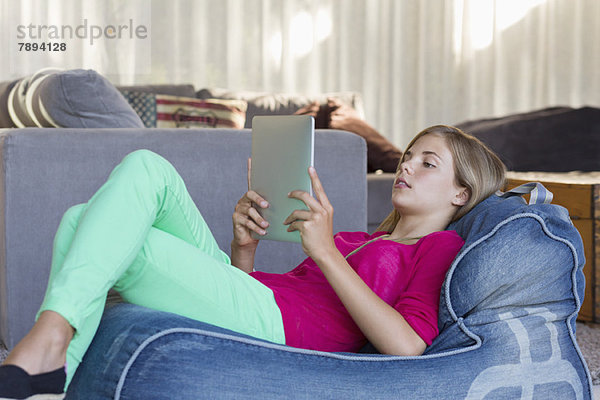 Mädchen auf einem Bohnensack liegend und mit einem digitalen Tablett