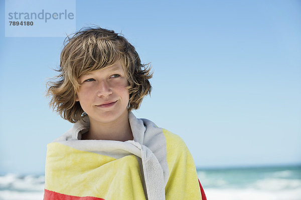 Junge in ein Handtuch gewickelt am Strand