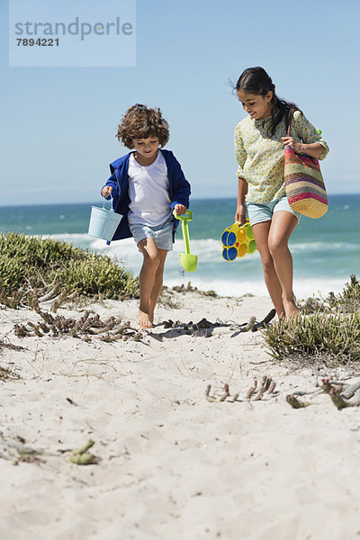 Ein Mädchen und ein Junge gehen am Strand spazieren.