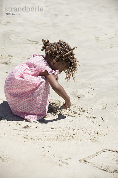 Mädchen spielt mit Sand am Strand