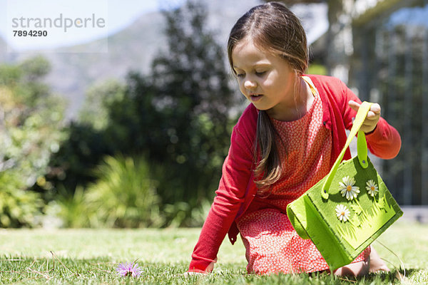 Mädchen beim Betrachten einer Blume im Rasen