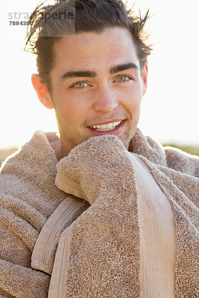 Porträt eines lächelnden Mannes in ein Handtuch gewickelt