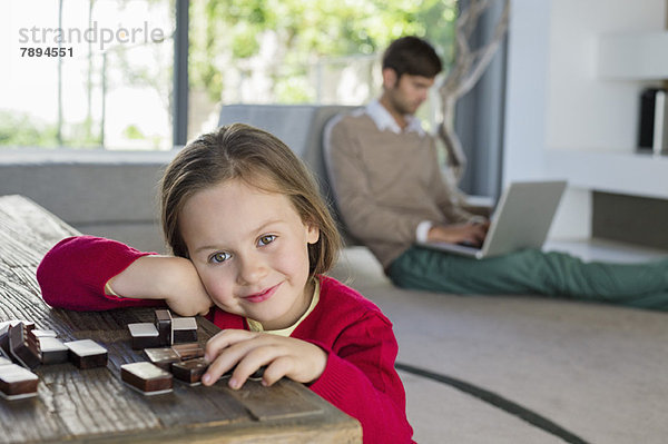 Porträt eines lächelnden Mädchens mit ihrem Vater mit einem Laptop im Hintergrund