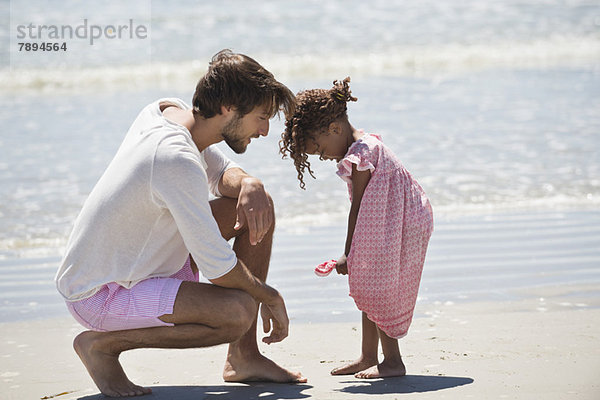 Mann spielt mit seiner Tochter am Strand