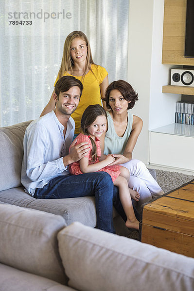 Eltern mit ihren Kindern sitzen im Wohnzimmer