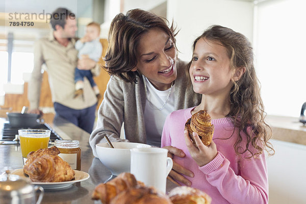 Mädchen frühstückt neben ihrer Mutter an der Küchentheke