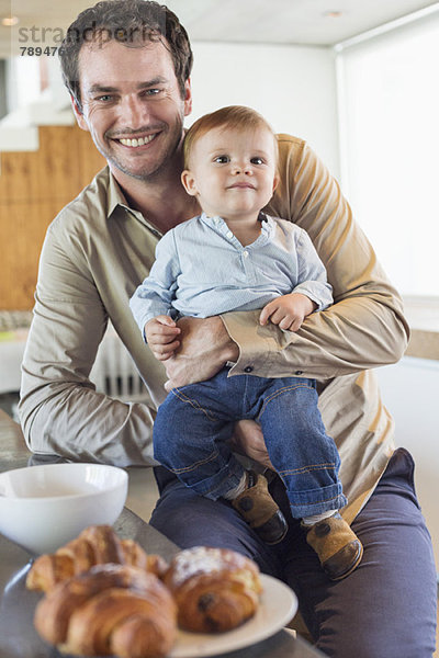 Mann mit seinem Sohn lächelnd an der Küchentheke