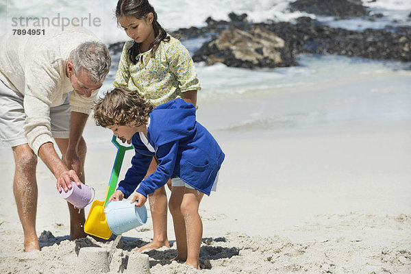Kinder beim Spielen mit ihrem Großvater am Strand