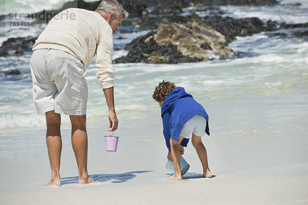 Junge spielt mit seinem Großvater am Strand