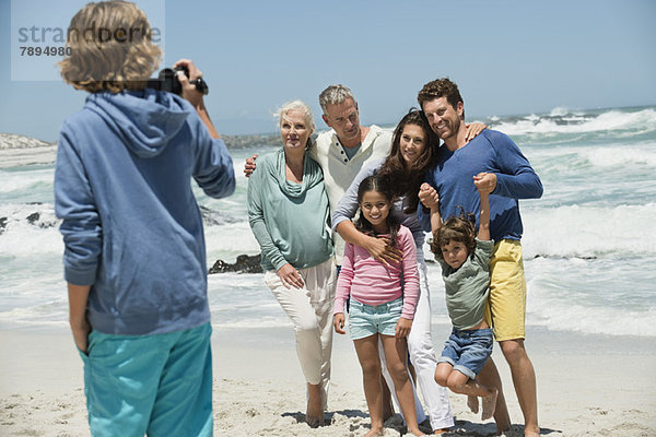 Junge filmt seine Familie mit einer Heimvideokamera am Strand.