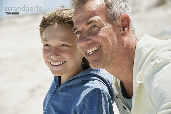 Mann lächelt mit seinem Enkel am Strand