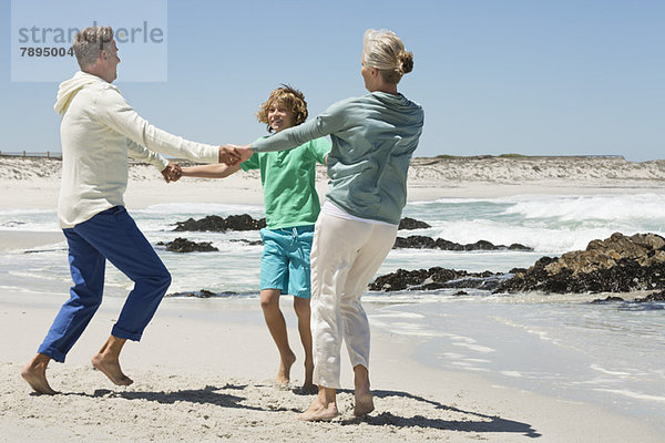 Junge spielt mit seinen Großeltern am Strand