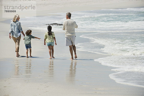 Kinder  die mit ihren Großeltern am Strand spazieren gehen
