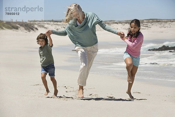 Frau spielt mit ihren Enkelkindern am Strand