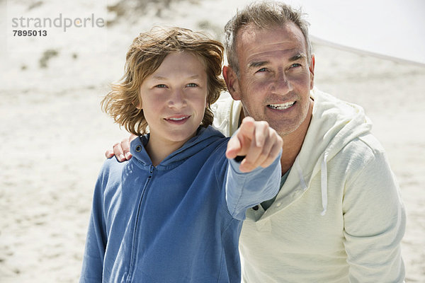 Junge zeigt mit seinem Großvater auf den Strand