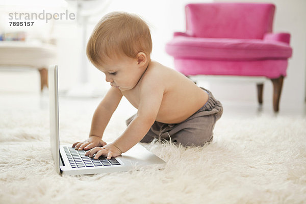 Baby Junge spielt mit einem Laptop