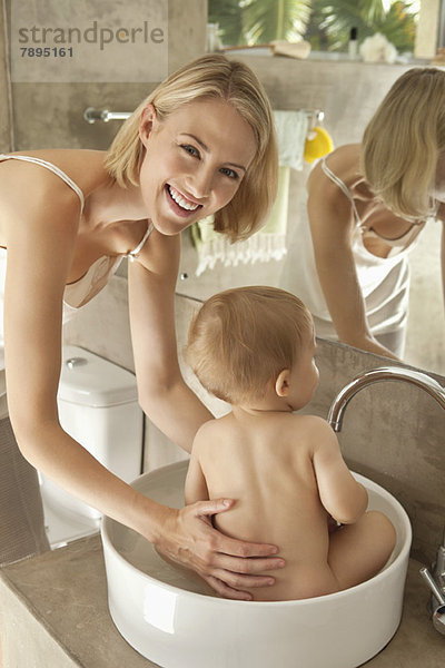 Frau badet ihr Baby in einer Waschschüssel