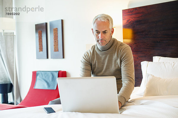Mann mit Laptop im Hotelzimmer