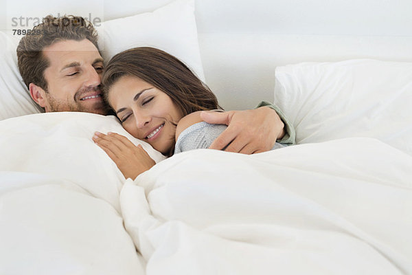 Lächelndes Paar auf dem Bett liegend