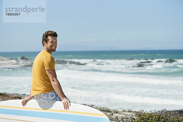 Mann auf einem Surfbrett am Strand sitzend