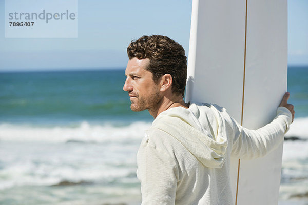 Mann mit Surfbrett am Strand