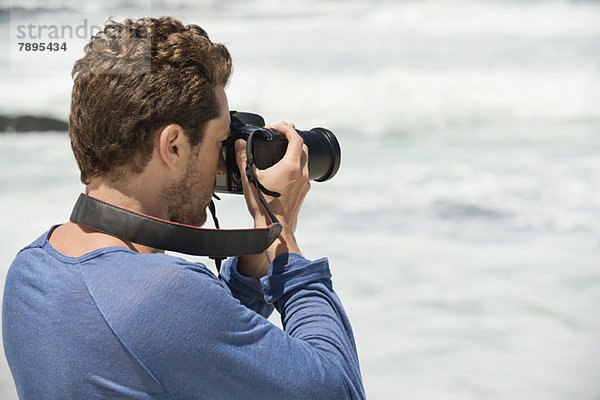 Mann fotografiert am Strand