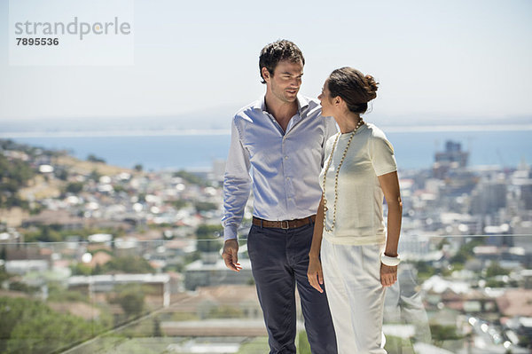 Ein Paar schaut sich auf einer Terrasse mit der Stadt im Hintergrund an.