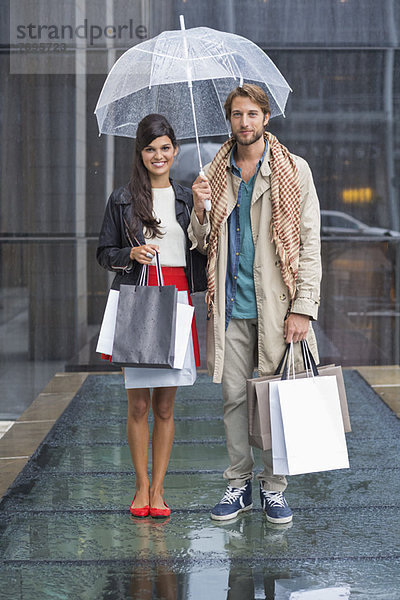 Paar stehend mit Einkaufstaschen bei Regen