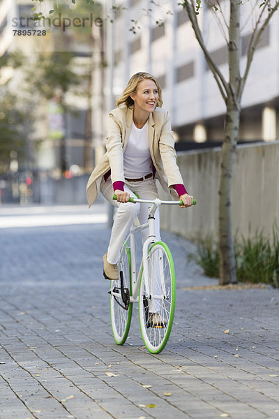 Frau fährt Fahrrad auf der Straße und lächelt