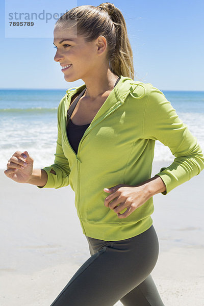 Lächelnde Frau beim Laufen am Strand