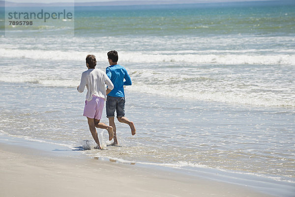 Zwei Männer  die am Strand rennen.